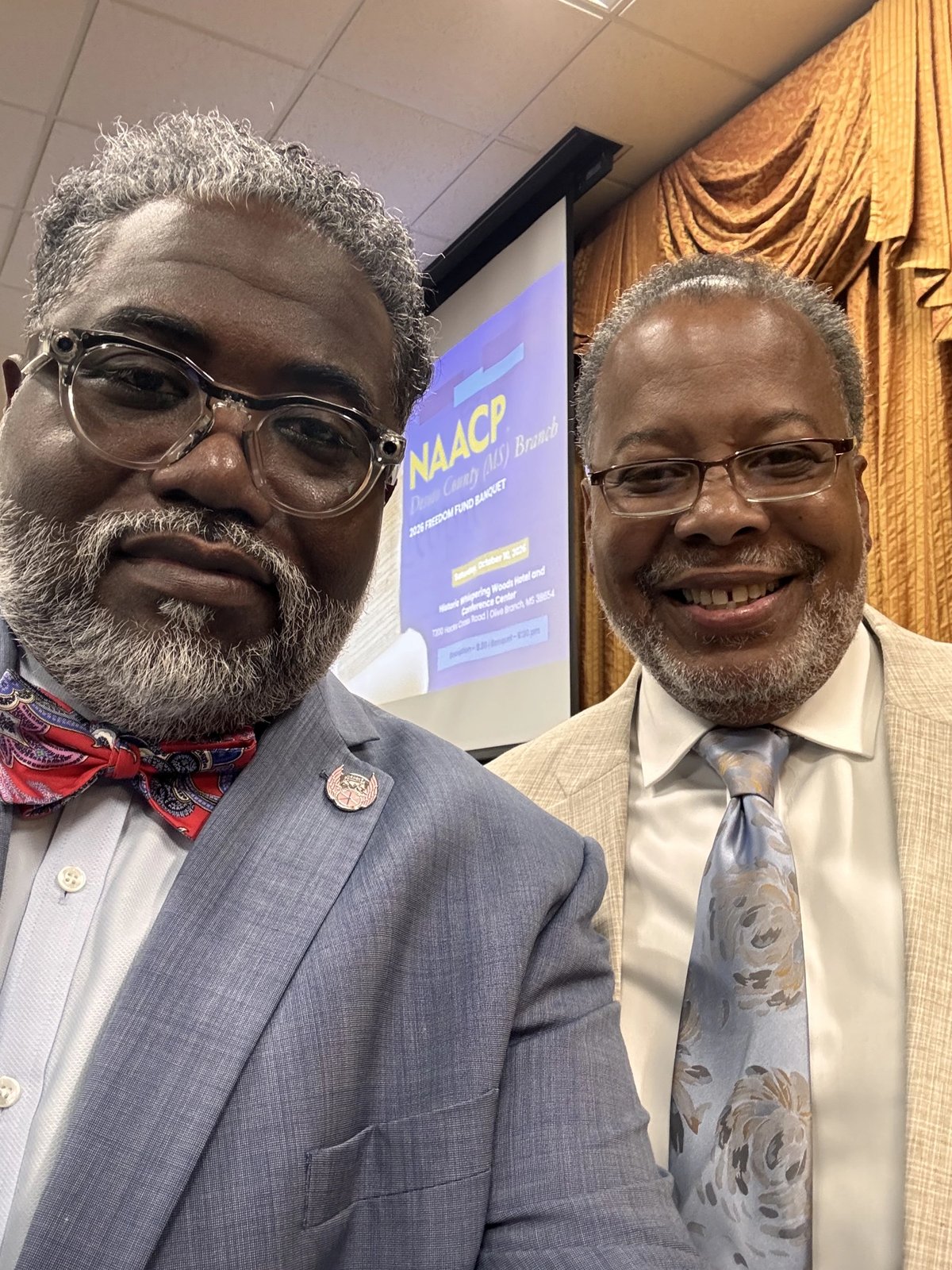 Two men at a banquet table with the NAACP DeSoto County Branch 2026 Freedom Fund Banquet program booklet