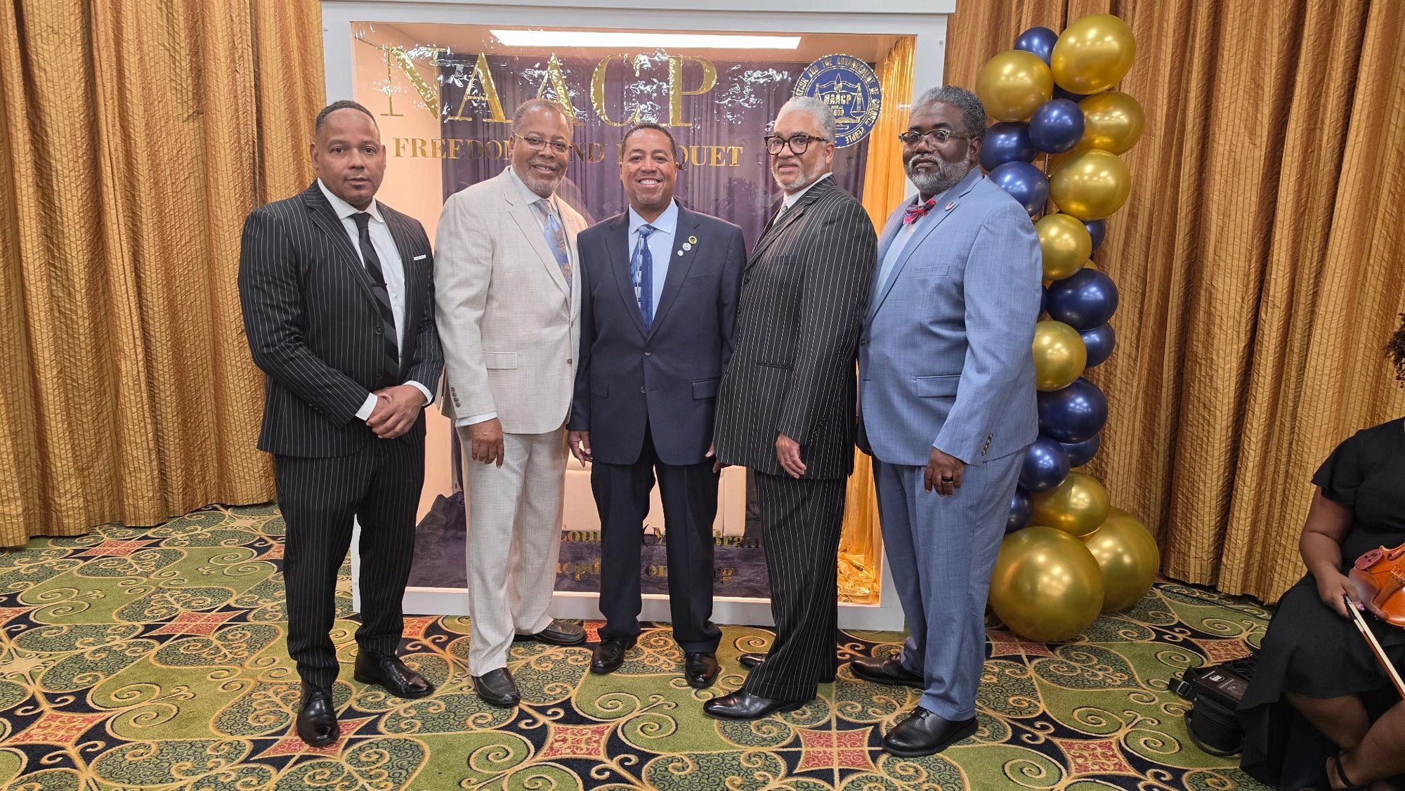 Five men in suits at the DeSoto County NAACP Freedom Fund Banquet step-and-repeat: Pastor Keith Caldwell, Pastor Robert Tipton Jr., Adrian Millsap, Kermit Moore and Kevin Bradshaw